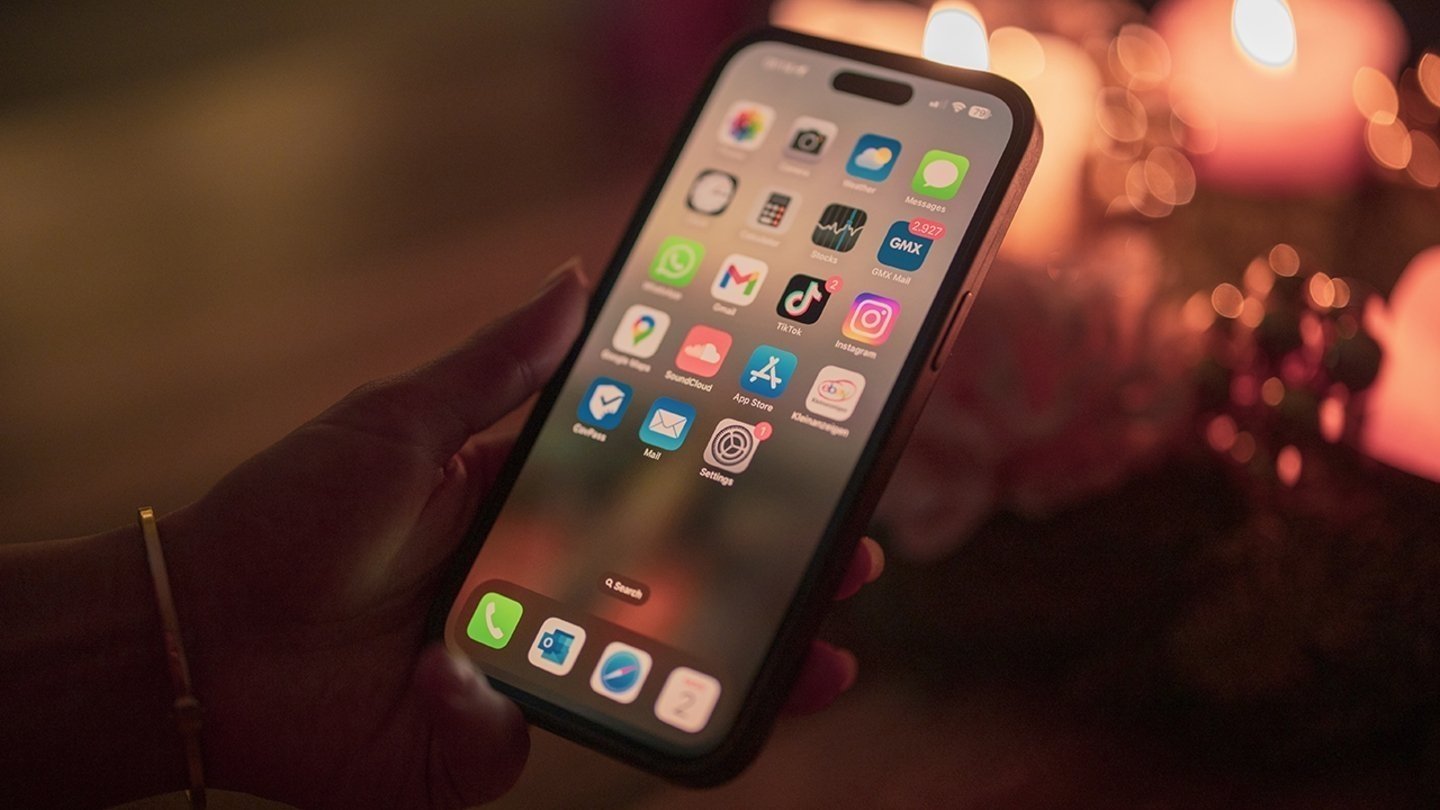 Usuario sosteniendo un iPhone con la pantalla de inicio encendida