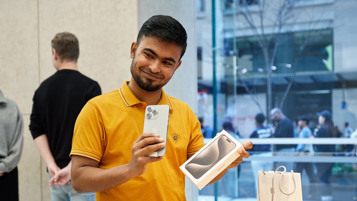 Un usuario comprando el iPhone 15 Pro, con el iPhone en una mano y la caja en la otra