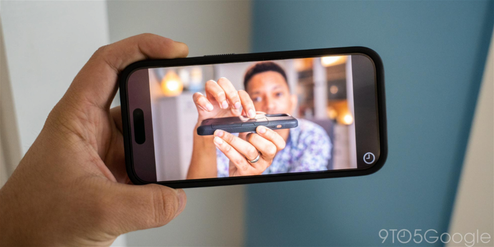 un hombre sostiene un iPhone 15 que reproduce un vídeo en el modo ambiente pantalla completa de YouTube